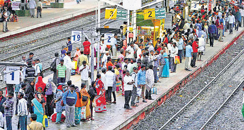 Passengers waiting for trains at KR Puram railway station in Bangalore on Sunday evening. DH Photo