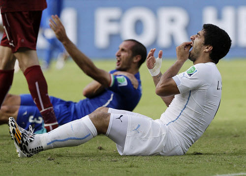FILE - In this June 24, 2014 file photo, Uruguay's Luis Suarez holds his teeth after biting Italy's Giorgio Chiellini's shoulder during the group D World Cup soccer match between Italy and Uruguay in Natal, Brazil. Sinking teeth into the shoulder of Giorgio Chiellini in a group-stage game led to a four-month ban from all football for the Uruguay striker. AP photo