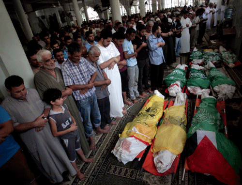 Palestinians mourners pray over the lifeless bodies of nine Palestinians killed in an early morning Israeli missile strike, at Bilal mosque during their funeral in the Khan Younis refugee camp, southern Gaza Strip, Saturday, July 19, 2014.  AP photo