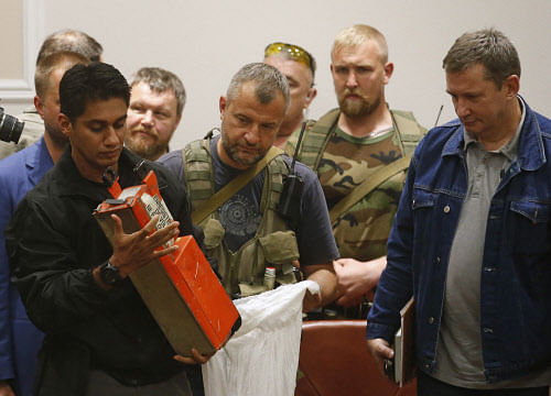 A Malaysian expert (L) examines a black box belonging to Malaysia Airlines flight MH17 during its handover from pro-Russian separatists, in Donetsk July 22, 2014. The remains of some of the 298 victims of the Malaysia Airlines plane downed over Ukraine were making their way to the Netherlands on Tuesday as Senior Ukrainian separatist leader Aleksander Borodai handed over the plane's black boxes to Malaysian experts. REUTERS