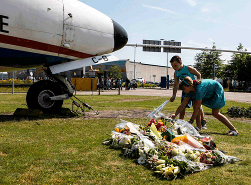 Two local children lay bouquets of flowers on the grass in front of a Dutch airplane during a national day of mourning for the victims killed in Malaysia Airlines Flight MH17 plane disaster last Thursday, in Eindhoven July 23, 2014. The Netherlands prepares to receive the bodies of the victims of the Malaysia Airlines flight MH17 crash on Wednesday. REUTERS