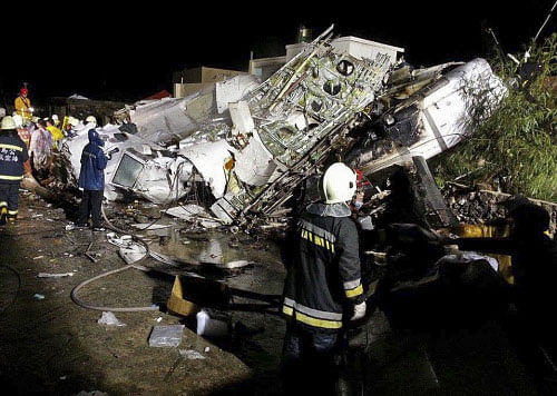 Rescue workers survey the wreckage of TransAsia Airways flight GE222 which crashed while attempting to land in stormy weather on the Taiwanese island of Penghu, late Wednesday, July 23, 2014. A plane landing in stormy weather crashed outside an airport on a small Taiwanese island late Wednesday, and a transport minister said dozens of people were trapped and feared dead. AP photo