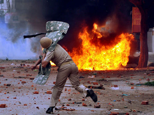 A policeman tries to control the mob during violent clashes between two communities in Saharanpur on Saturday. PTI