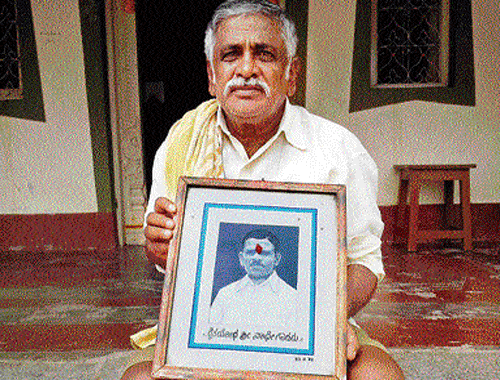Nagaraj with a photograph of Nathappa, who was killed in the police firing at Gejjalagere in Maddur taluk of Mandya district, on November 24, 1982. DH photo