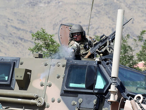 A NATO soldier opens fire in an apparent warning shot in the vicinity of journalists near the main gate of Camp Qargha, west of Kabul, Afghanistan. A man dressed in an Afghan army uniform opened fire Tuesday on foreign troops at a military base, causing casualties, an Afghan military spokesman said. AP Photo