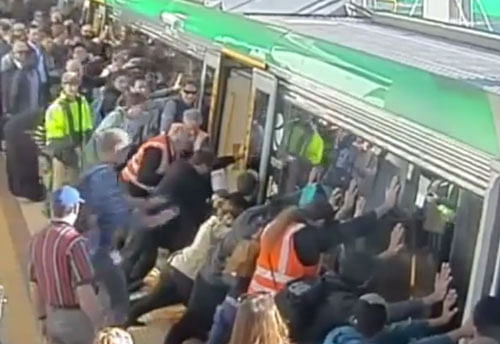Australians tilting a train to free a commuter whose leg was trapped between a carriage and a platform. TV grab