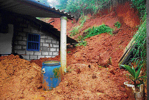 A house was damaged when earth caved in at Bhagavathi Nagara in Madikeri on Wednesday.  dh photo