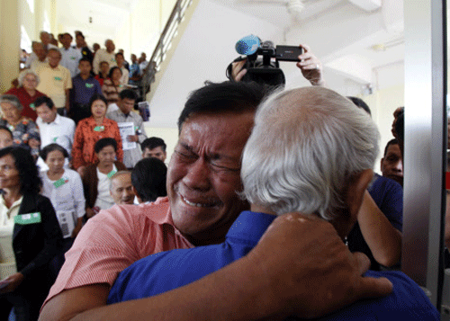 Cambodian former Khmer Rouge servitors, Soum Rithy, left, and Chum Mey, right, embrace each other after the verdicts were announced, at the U.N.-backed war crimes tribunal in Phnom Penh, Cambodia, Thursday, Aug. 7, 2014. AP photo