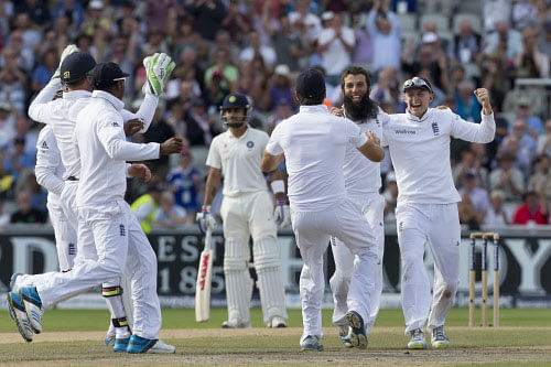 England's Moeen Ali, second right, celebrates with teammates after taking the wicket of India's Cheteshwar Pujara for 17 on the third day of the fourth test match of their five match series at Old Trafford cricket ground, in Manchester, England, Saturday, Aug. 9, 2014. AP photo