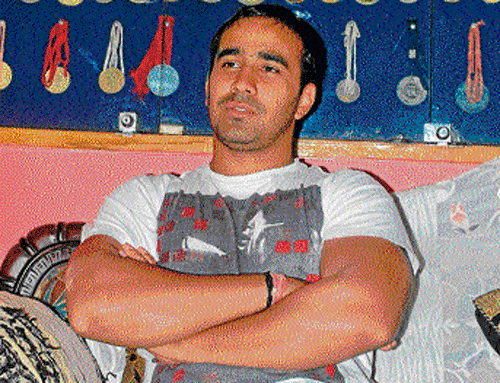 Sushil Kumars brother Amarjeet poses in front of the wrestlers medals.