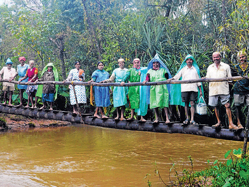 Villagers cross the precarious bridge over Bedakki streamnear Kalasa village in Chikmagalur district. DH photo