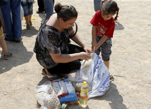 An Iraqi woman and child displaced by the violence in their country look at the aid they received from a Chaldean Catholic Church truck in Beirut. Reuters photo