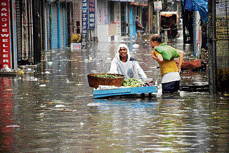 Knee-deep: A vegetable vendor moves through a waterlogged street  in Patna on Thursday. PTI
