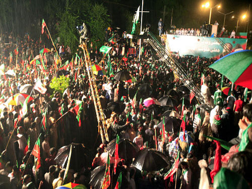 Supporters of Pakistan's cricketer-turned-politician Imran Khan take part in an anti government rally in Islamabad, Pakistan. Tens of thousands of anti-government protesters gathered in Pakistan's capital Islamabad late Friday in the pouring rain following the arrival of convoys led by Khan and a fiery anti-Taliban cleric. AP Photo