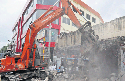 BBMP demolishes shops constructed on a stormwater drain in Shivajinagar, on Monday. DH photo