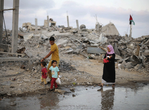 Palestinians walk next to the ruins of houses, which witnesses said were destroyed during the Israeli offensive, on the fifth day of ceasefire in Khan Younis in the southern Gaza Strip August 18, 2014. Reuters photo