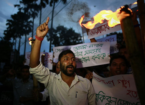 Scheduled caste activists hold lighted torches and shout slogans in Gauhati, Assam, India, as they protest against the ongoing violence in Golaghat town in the state, Thursday, Aug. 21, 2014. AP photo