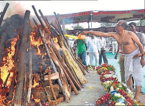 Bidding adieu: Fans and admirers watch the final rites of U R&#8200;Ananthamurthy in Bangalore on Saturday. (Below) His son Sharath lights the funeral pyre. DH Photos