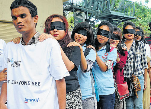 People walk blindfolded with the help of a visually  challenged person at the Blind Walk on Sunday. DH Photo