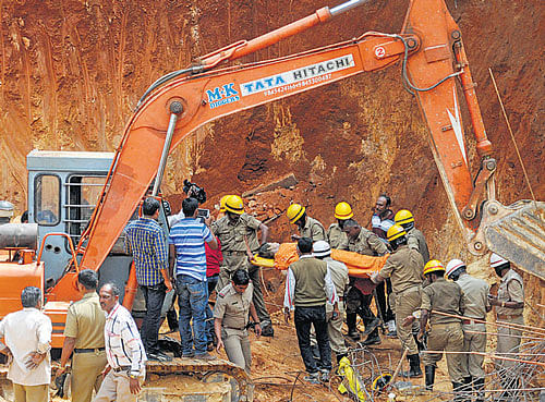 Fire personnel retrieve the body of a constructionworker who was buried alive as soil caved in on him at a construction site on Infantry Road on Monday. DH PHOTO