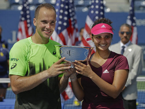 Bruno Soares, left, and Sania Mirza pose for photos with the championship trophy after defeating Abigail Spears and Santiago Gonzalez in the mixed doubles final of the 2014 U.S. Open tennis tournament, Friday, Sept. 5, 2014, in New York.AP photo