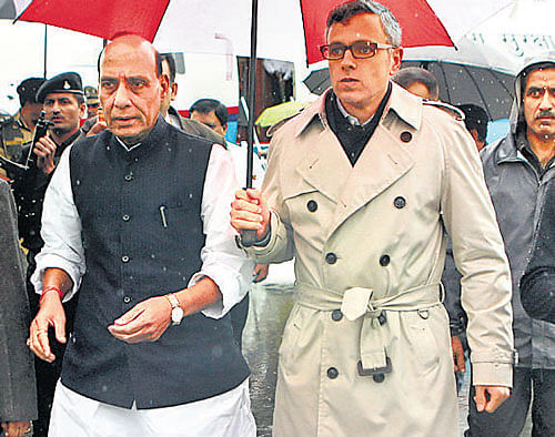 Union Home Minister Rajnath Singh walks under an umbrella held by Chief Minister of Jammu and Kashmir Omar Abdullah after he arrived to inspect flood-affected areas of the state in Srinagar, on Saturday. AP