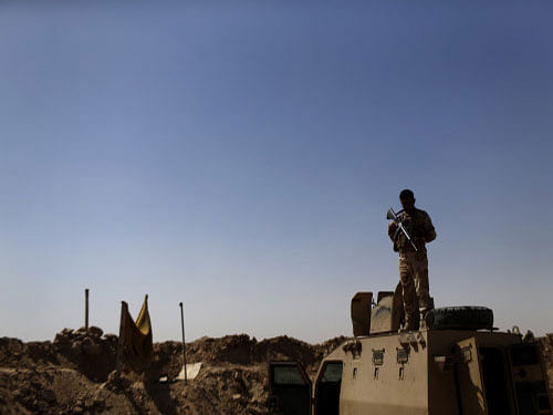 A Kurdish Peshmerga fighter stands guard atop an armored vehicle at a combat outpost on the outskirts of Makhmour. The United States has launched its first air strikes in Iraq's Sunni Arab heartland, bombing jihadists near a key dam on the Euphrates River, the US military said today. AP photo