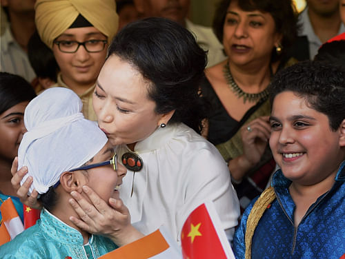China's first lady Peng Liyuan kisses a student during a visit to the Tagore International School in New Delhi on Thursday. PTI Photo