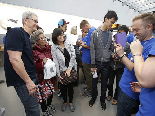 Tim Cook, CEO of Apple Inc takes a photograph with Apple customers at the Apple Store during the launch and sale of the new iPhone 6 on Friday, Sept 19, 2014 Palo Alto, Calif. AP photo