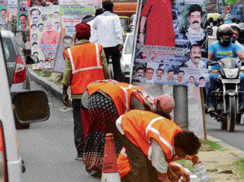 Palike workers paint the kerb stones of the median strip on a prominent road in Bangalore on Tuesday. DH PHOTO