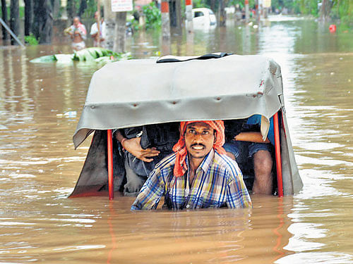 A man pulls his rickshaw through the flood water in Anil Nagar area of Guwahati on Tuesday. PTI