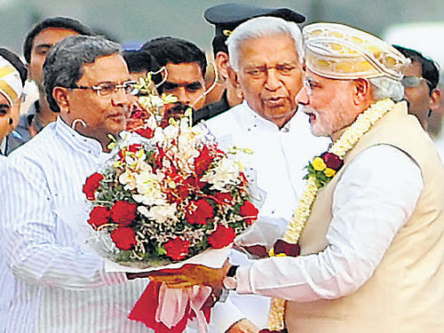 Chief Minister Siddaramaiah welcomes Prime Minister Narendra Modi on his arrival at HAL airport in Bangalore on Tuesday. Modi is on a two-day visit to Karnataka. Also seen is Governor Vajubhai Rudabhai Vala. DH Photo