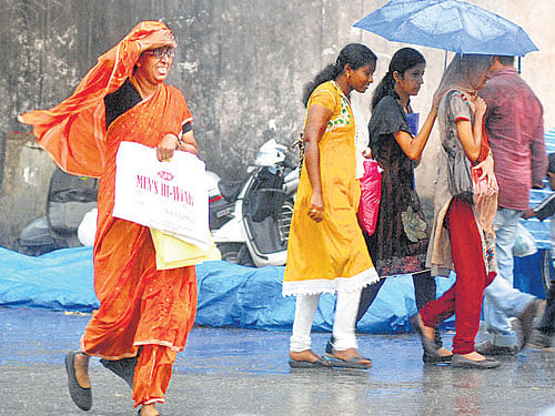 Women run for cover during a sudden downpour at Shivajinagar in the City on Wednesday. DH photo