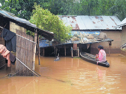 A woman sitting in a boat outside her house at a flooded village in Sonaruguri in Nagaon on Thursday. PTI