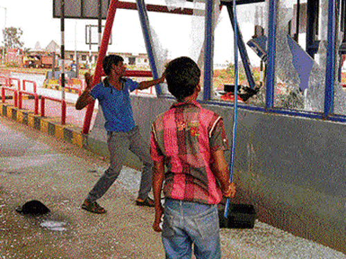 Protesters damage a toll booth on NH 13 near Hitnal village on the outskirts of Koppal on Thursday, following an accident which claimed the life of a cyclist. DH photo