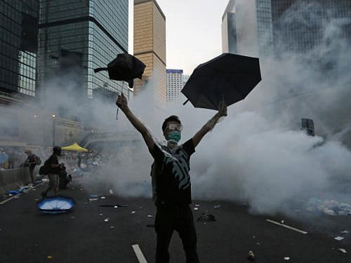 A protester raises his umbrellas in front of tear gas which was fired by riot police to disperse protesters blocking the main street to the financial Central district outside the government headquarters in Hong Kong. Reuters photo