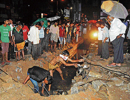 Rescue workers search for Geeta Lakshmi, who fell into a drain on Bannerghatta Road on Monday night. dh photo