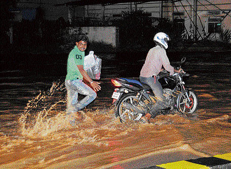 Caught unawares: Motorcyclists found commuting difficult due to waterlogging on Airport Road on Monday evening. DH photo