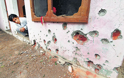 A man looks at the mortar shell marks on the wall of his house after firing from the Pakistani side at village Chilayari in Samba district, about 50 km from Jammu, on Wednesday. PTI