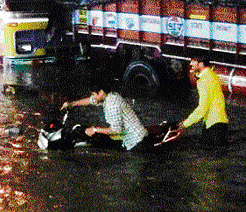 Two men wade through the waist-high water with their bike in Sultanpet. DH photo
