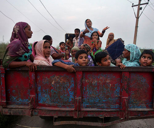 Villagers sit in a tractor trolley as they move to safer places at Devi Garh village near Jammu / Reuters Photo