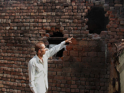 A man shows the wall of his house damaged during shelling from the Pakistani side at Nanha village in Ramgarh sector, about 52 kms from Jammu. After nine days of heavy firing and mortar shelling from across the border, firing de-escalated along the 192-km long International Border in Jammu frontier overnight with Pakistan opening fire on four border out posts in Kathua district. PTI photo