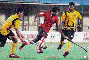 Umesh KR (centre) of Karnataka attempts to dribble past KB Rinil Singh and Chandan Aind of Army XI in the Bengaluru Cup in Bangalore on Friday. DH photo