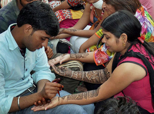 Women get their palms and arms decorated with mehandi on the eve of Karwa Chauth in Gurgaon on Friday. PTI Photo