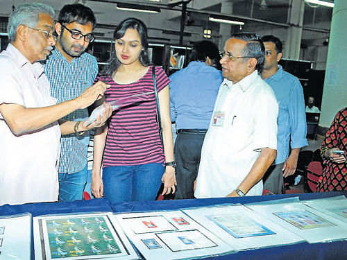 Philatelist M K Krishnaiah explains his collection to visitors at the Philatelic exhibition in Head Post office, Pandeshwar in Mangalore DH Photo