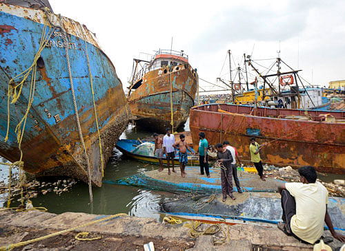 People stand on boats damaged by strong winds caused by Cyclone Hudhud in the southern Indian city of Visakhapatnam October 13, 2014. Cyclone Hudhud powered its way inland over eastern India on Monday, leaving a swathe of destruction but the loss of life appeared limited after tens of thousands of people sought safety in storm shelters, aid workers and officials said. REUTERS