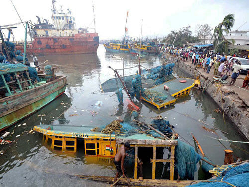 Fishermen watch their Cyclone damaged fishing boats in Vishakapatnam. The port city of Visakhapatnam was today limping back to normalcy with restoration of essential supplies and public transportation services, three days after it was battered by Cyclone Hudhud. PTI photo