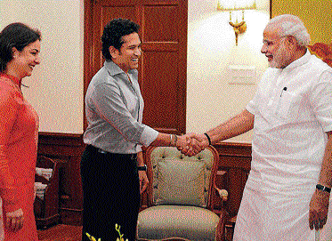 Prime Minister Narendra Modi shakes hands with Sachin Tendulkar as the cricket legend's wife Anjali looks on at a meeting in New Delhi on Thursday. PTI