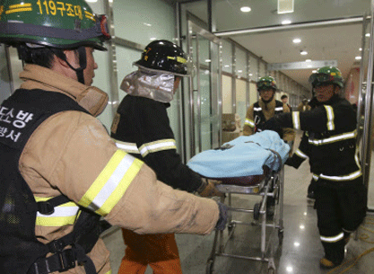 Rescue workers carry an injured person on a stretcher after a ventilation grate was collapsed at an outdoor theater in Seongnam, South Korea, Friday, Oct. 17, 2014. Fourteen people were feared dead Friday after the ventilation grate collapsed during a concert by popular girls' band 4Minute, officials said. AP