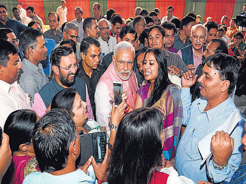 Prime Minister Narendra Modi poses for photographs with reporters during the Diwali Mangal Milan at BJP headquarters in New Delhi on Saturday. I&B Minister Prakash Javadekar is also seen. PTI